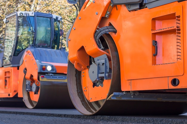 Wegenbouw. twee gladde walsverdichters (stoomwals) aan het werk, nieuw asfalt persen