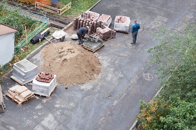 Wegenwerkers bouwen een baan Veel bouwmaterialen op de stoep