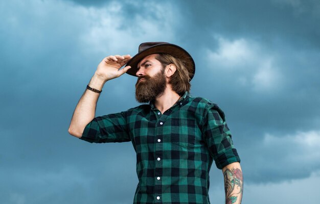 Wegkijken brutale hipster met snor in hoed mannequin draag casual westerse kleding mannelijke schoonheid standaard ziet er zo trendy uit Zelfverzekerde en knappe man bebaarde man texas brutale cowboy