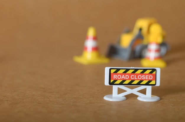 Wegsluitingswaarschuwing met speelgoedkegels en machinerie bouwplaats in miniatuur
