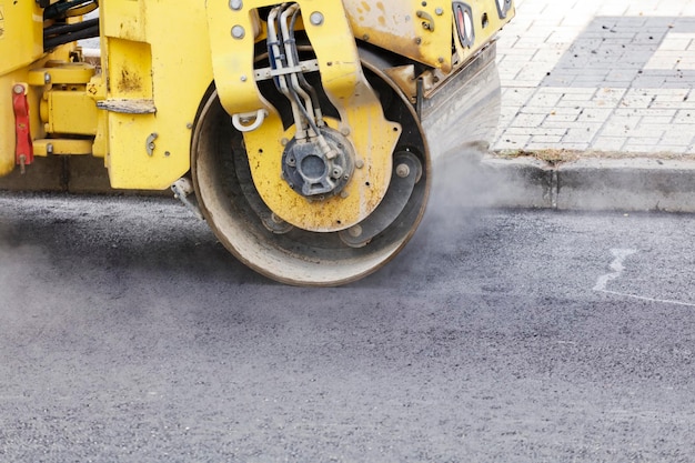 Wegwals en asfalteermachine op de bouwplaats, met heet beton en rook