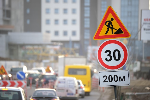 Wegwerkzaamheden die verkeersborden waarschuwen voor bouwwerkzaamheden op straat in de stad en langzaam rijdende auto's