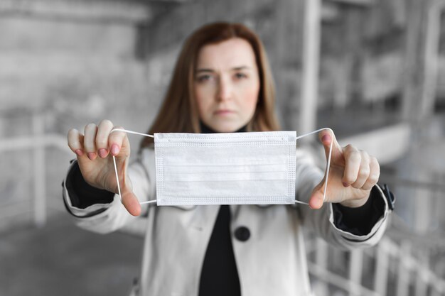 Wegwerp medisch masker in de handen van een vrouw. Vrouw zet een beschermend masker op het gezicht van een man. Covid19, Coronavirus.