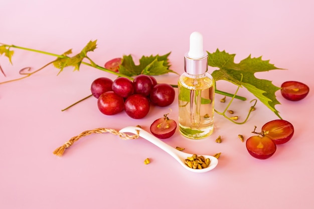 Wei op basis van druivenpitolie in een cosmetische fles tegen de achtergrond van een wijnstok roze achtergrond natuurlijke cosmetica