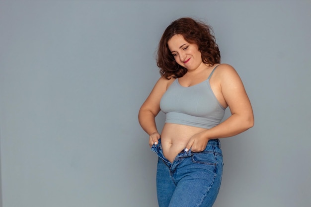 weight loss and overweight problem a fat woman in a tank top and jeans is trying to button up or pu