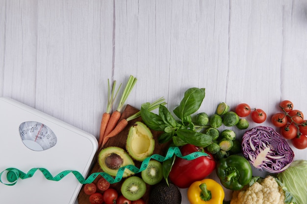 Weight loss scale with different fruits and vegetables. top view.