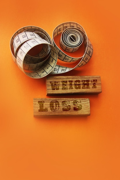 Weight loss words on wooden blocks sign with measure tape on orange background