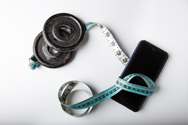 Weights plates and smartphone with measuring tape isolate in white background