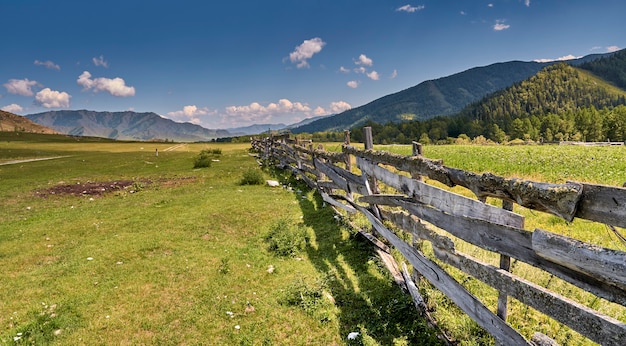 Weiland in de bergen is omheind met een hekwerk van oude planken. Altai