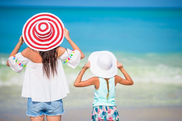 Weinig aanbiddelijk meisje en jonge moeder bij tropisch strand