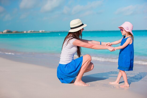 Weinig aanbiddelijk meisje en jonge moeder bij tropisch strand
