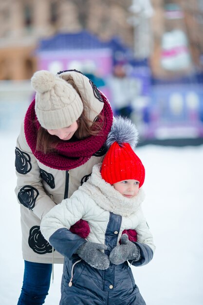 Weinig aanbiddelijk meisje met haar moeder die op ijsbaan schaatst