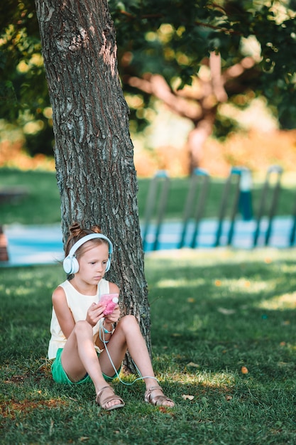 Weinig aanbiddelijke meisje het luisteren muziek in het park