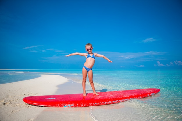 Weinig aanbiddelijke meisjespraktijk het surfen positie bij strand