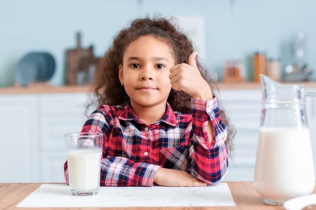 Weinig Afrikaans-Amerikaans meisje met melk in keuken