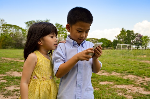 Weinig Aziatisch jongen en meisje gebruiken de slimme telefoon / tablet om het spel te spelen.