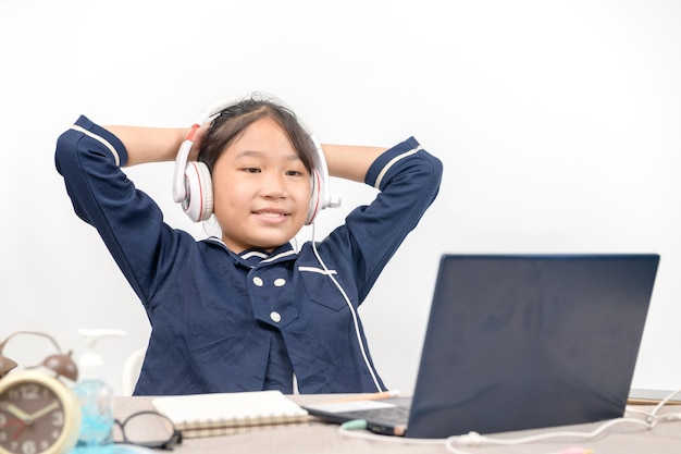 Weinig Aziatisch meisje dat huiswerk op laptop doet