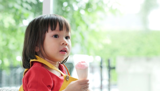 Foto weinig aziatisch meisje dat roomijs in een knapperige kegel eet