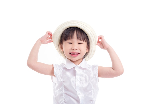 Weinig Aziatisch meisje die hoed en glimlachen over witte achtergrond dragen