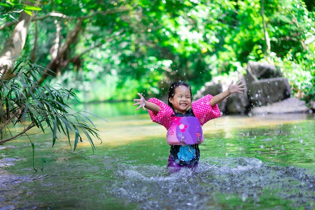 Weinig Aziatisch meisje die opblaasbare kokers dragen die aardwater op vakantie spelen