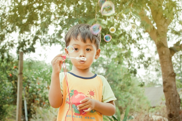 Weinig Aziatische jongen die met bellentoverstokje blaast zeepbels