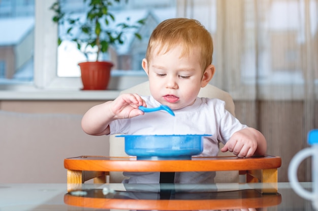 Weinig babyjongen die met een lepel leert eten