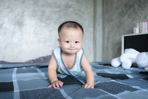 Weinig babyjongen die op het bed thuis kruipen