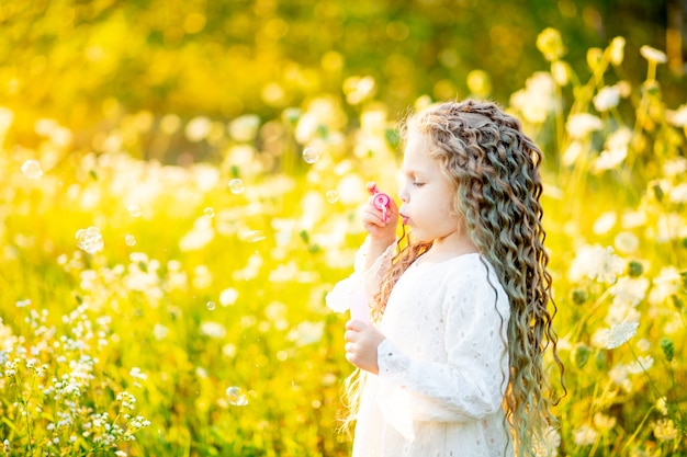 Weinig gelukkig meisje in het veld met bloemen