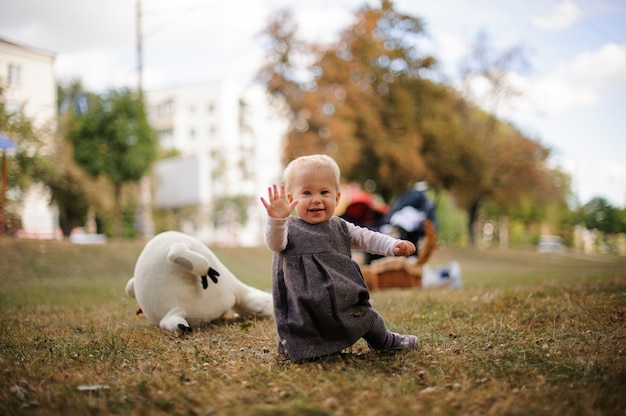 Weinig glimlachend babymeisje dat op grond van een park loopt