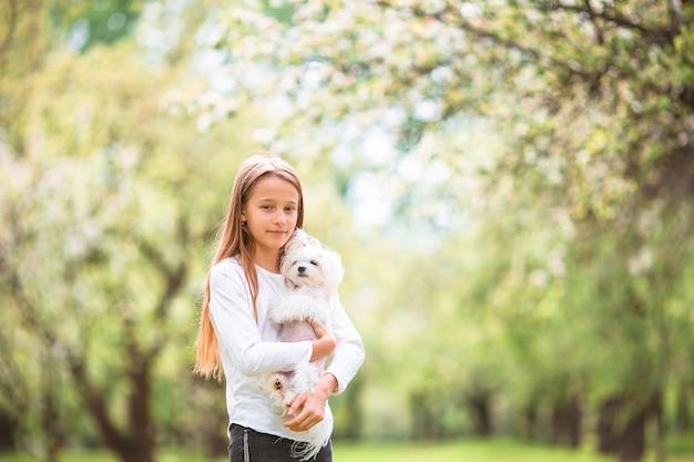 Weinig glimlachend meisje spelen en knuffelen puppy in het park