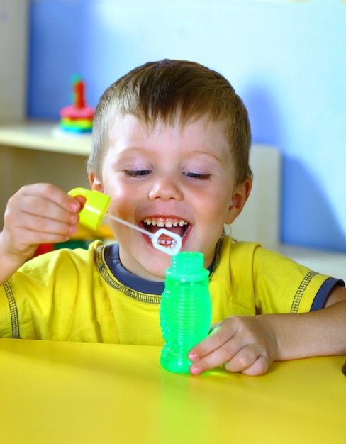 Weinig glimlachende jongen speelt met zeepbels.