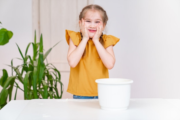 Weinig grappig meisje houdt handen in bloem over haar wangen. culinaire hobby voor kinderen.