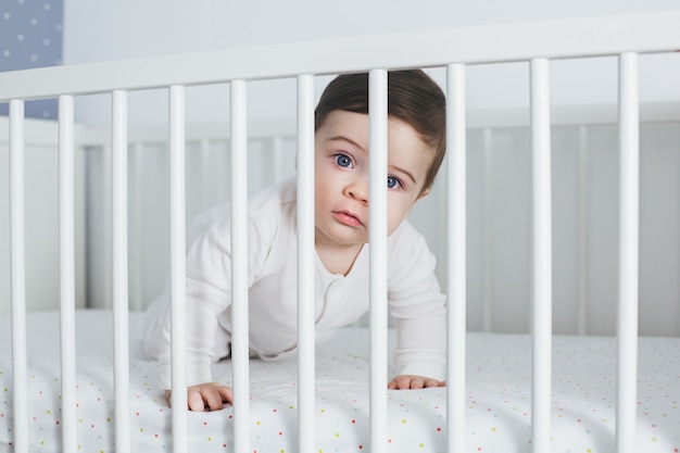 Weinig grappige jongen die in babybed ligt