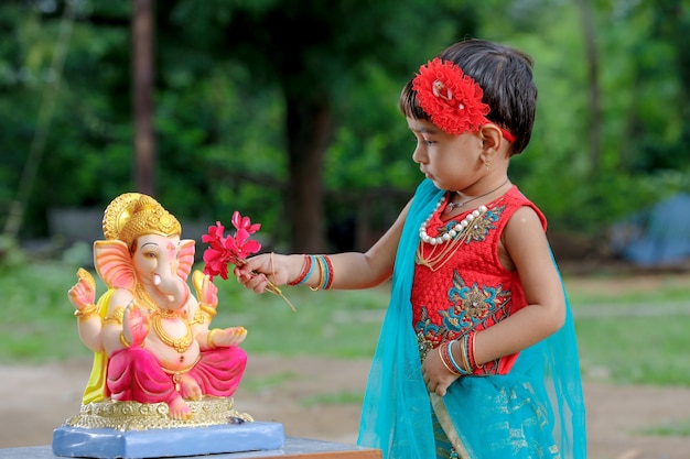 Weinig Indisch meisjeskind met Lord Ganesha en het bidden