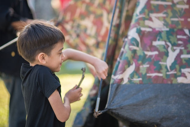 Weinig jongen die een tent voor het kamperen met de zomertijd van de familievakantie bouwt