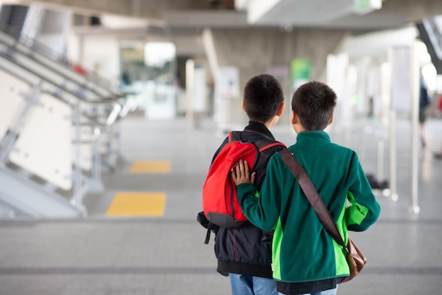 Weinig jongen die elektrisch kaartje koopt en in het openbare hemeltreinstation loopt met familie