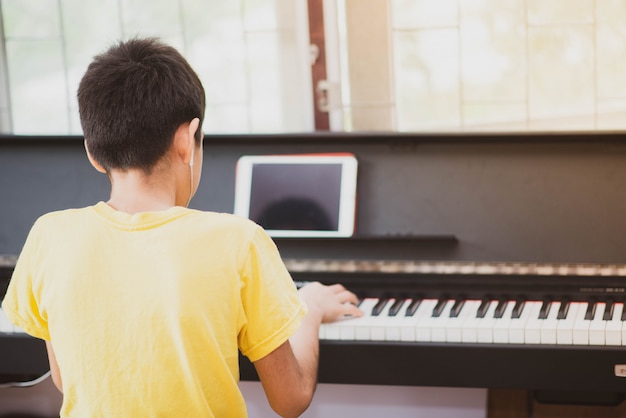 Weinig jongen die piano online digitale tablet thuis uitoefenen