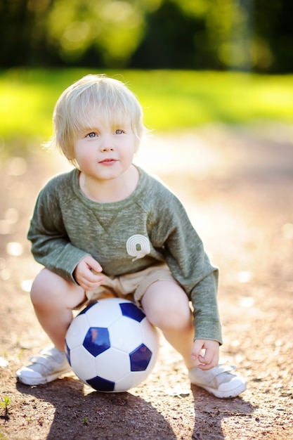 Weinig jongen die pret heeft die een voetbal / een voetbalspel op de zomerdag speelt