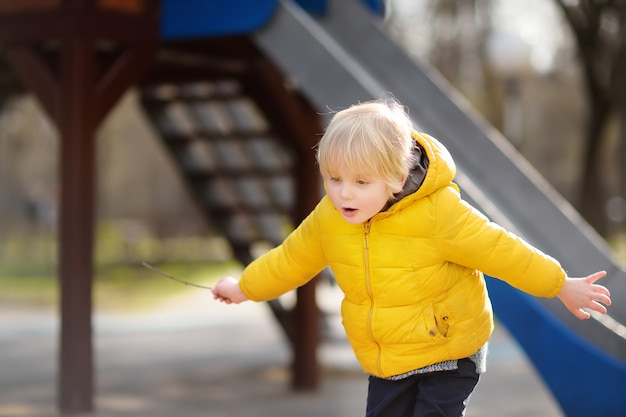 Weinig jongen die pret op openluchtspeelplaats op de lente heeft of dag valt