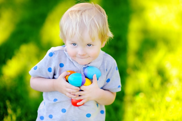 Weinig jongen die voor paasei in de lentetuin jaagt op Pasen-dag. Schattig klein kind feest vieren