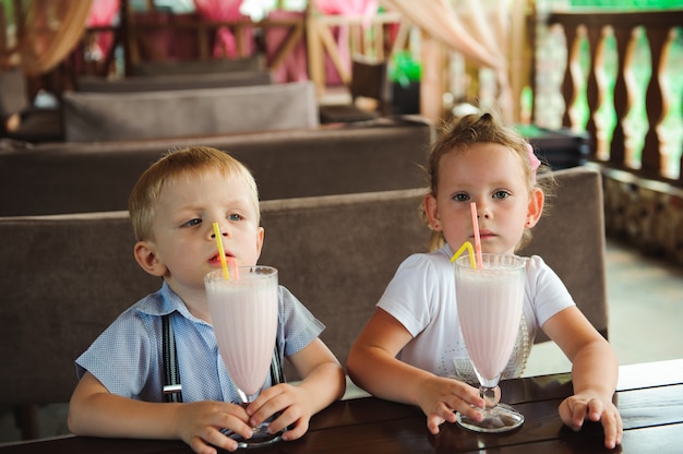 Weinig jongen en meisjes het drinken milkshakes in een koffie in openlucht.