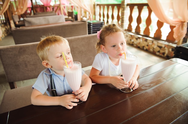 Weinig jongen en meisjes het drinken milkshakes in een koffie in openlucht.