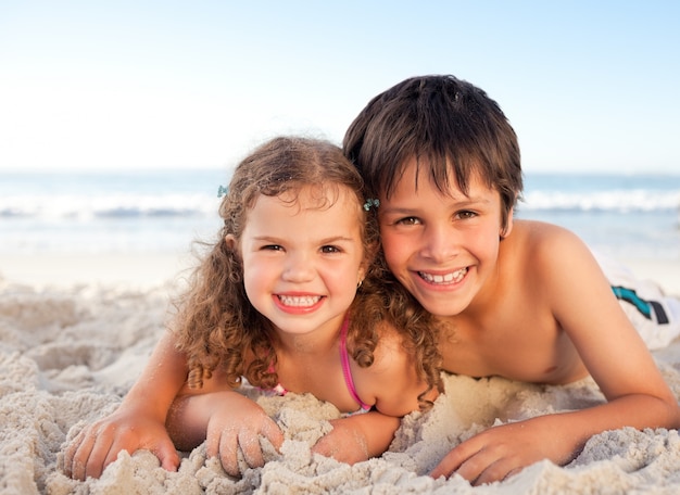 Foto weinig jongen en zijn zuster die op het strand liggen