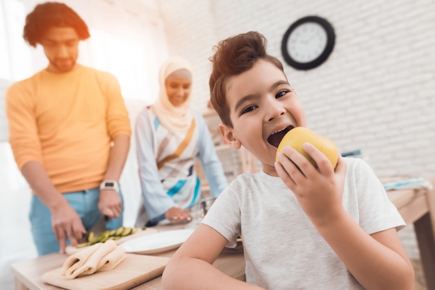 Weinig jongen in de keuken die een appel eet.