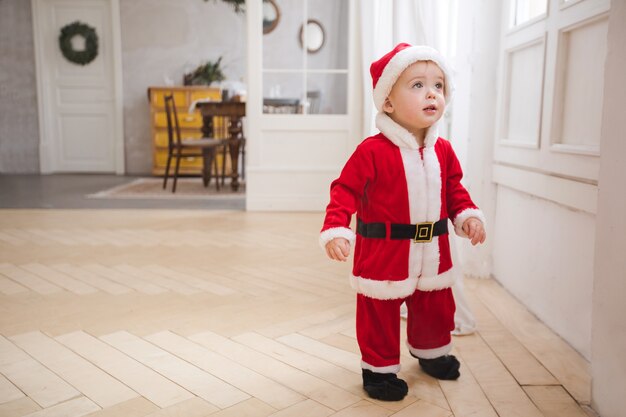 Weinig jongen in kerstmiskostuum die zich in ruimte bevinden