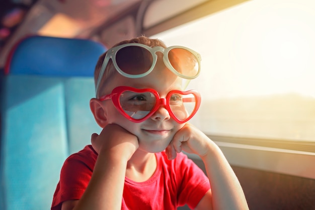 Weinig jongen in sommige zonglazen die door trein tijdens vakantie reizen