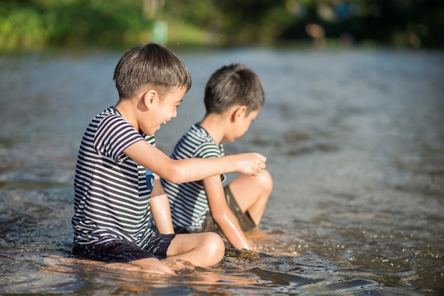 Weinig jongenszitting samen bij het rivierkanaal