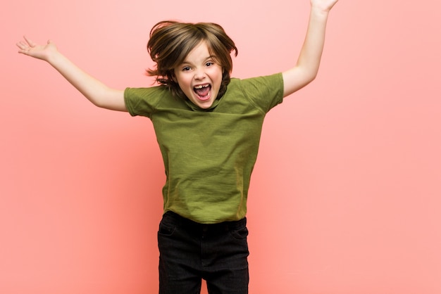 Foto weinig kaukasische jongen die tegen pink speelt