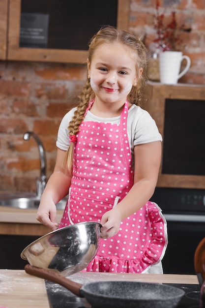 Foto weinig leuk meisje dat pret in de keuken heeft