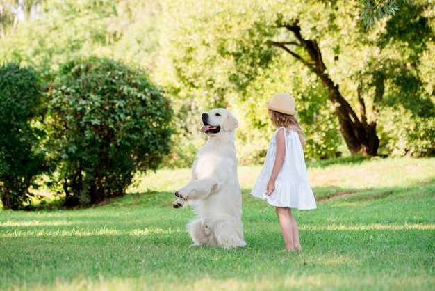 Weinig leuk peutermeisje dat met haar grote witte herdershond speelt.
